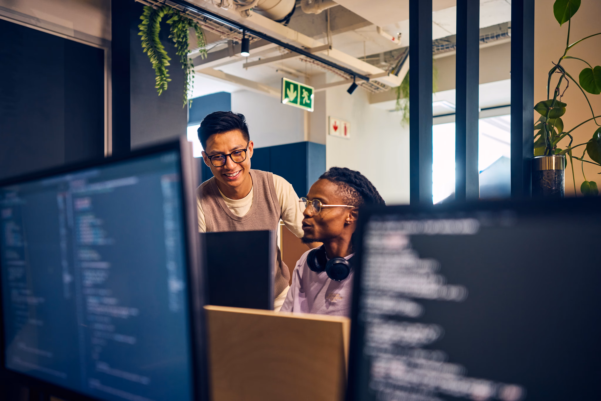 Dois empreendedores analisando código em telas de computador em um escritório de startup