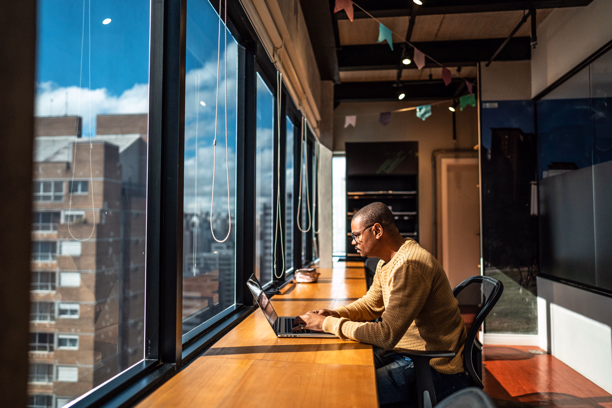 Fundador de startup trabalhando em um laptop em um escritório com vista para a cidade